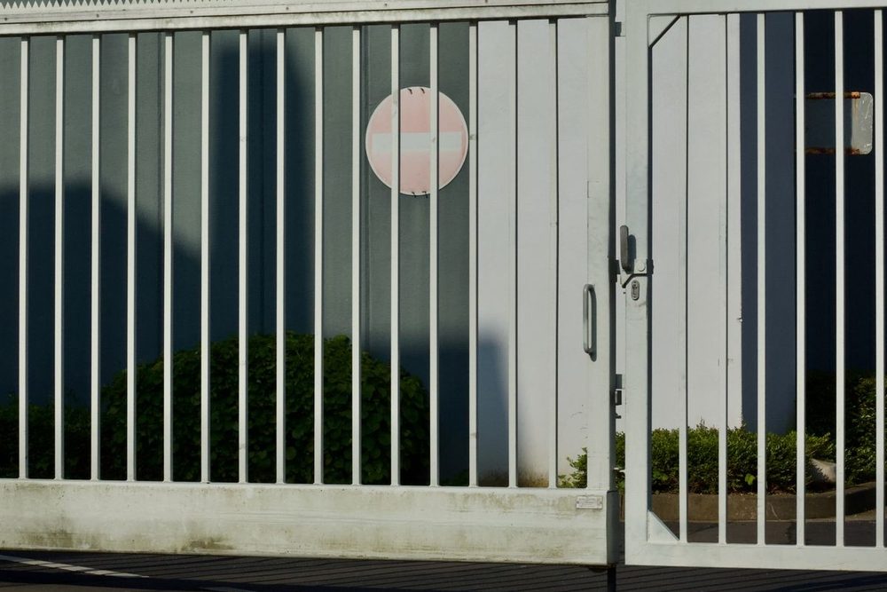 Weißes Schiebetor mit Zaunfeld an einem Gewerbegebäude