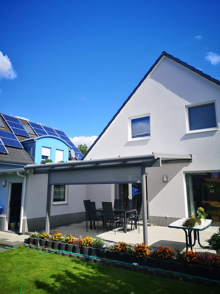 Terrassendach an einem weißen Giebelhaus mit Gartenterrasse